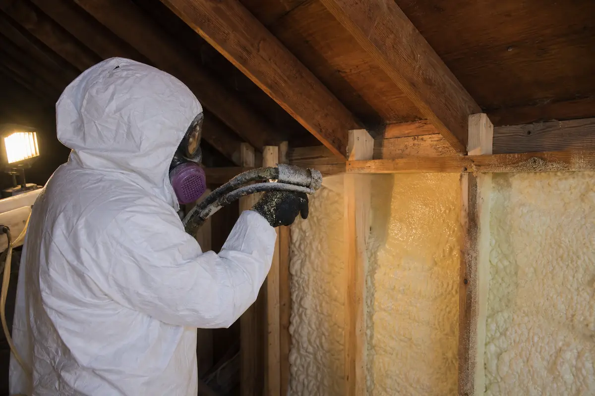 Installer applying closed-cell spray foam insulation to wall framing in a Winnipeg home